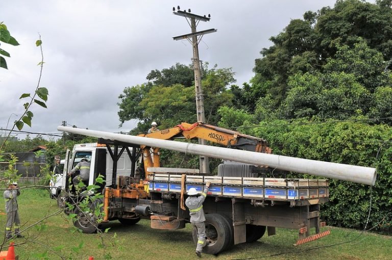 Operários instalam um poste de energia elétrica