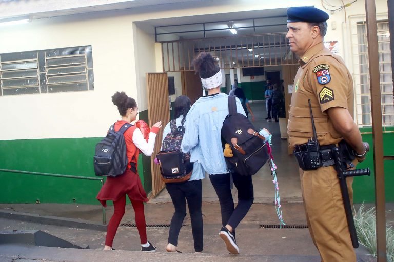 Policial faz a segurança de alunos na porta da escola