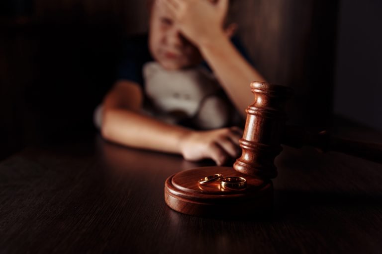 Foto desfocada de uma criança, um par de alianças e um martelo de juiz